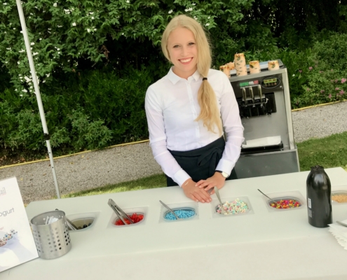 blonde Servicekraft gibt Frozen Joghurt aus mit frozen Joghurt Maschine aus und Toppings