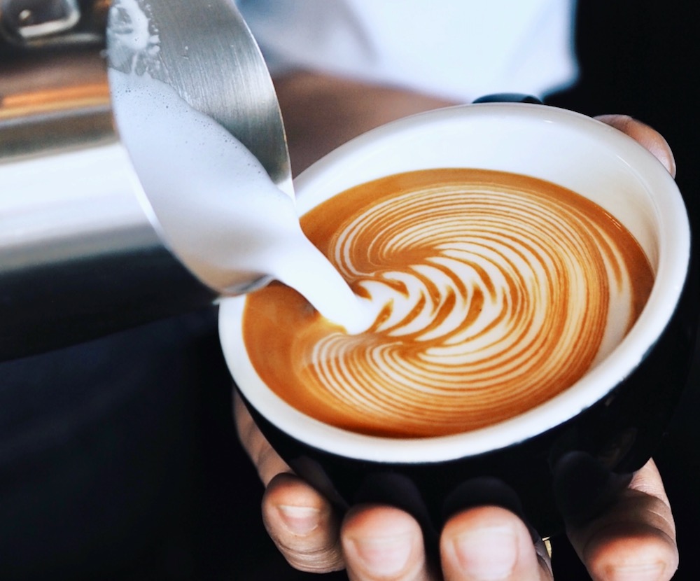 Barista giesst Milch aus Kännchen in Tasse ein Latte Art mobile Erpressobar