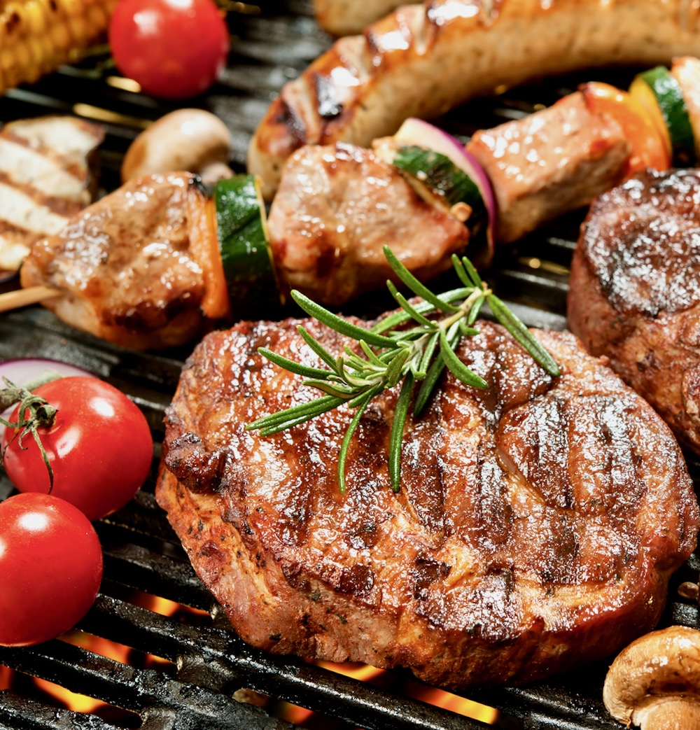 Fleisch Bratwurst auf Grill mit Tomaten und Rosmarien für BBQ Grillcatering Special