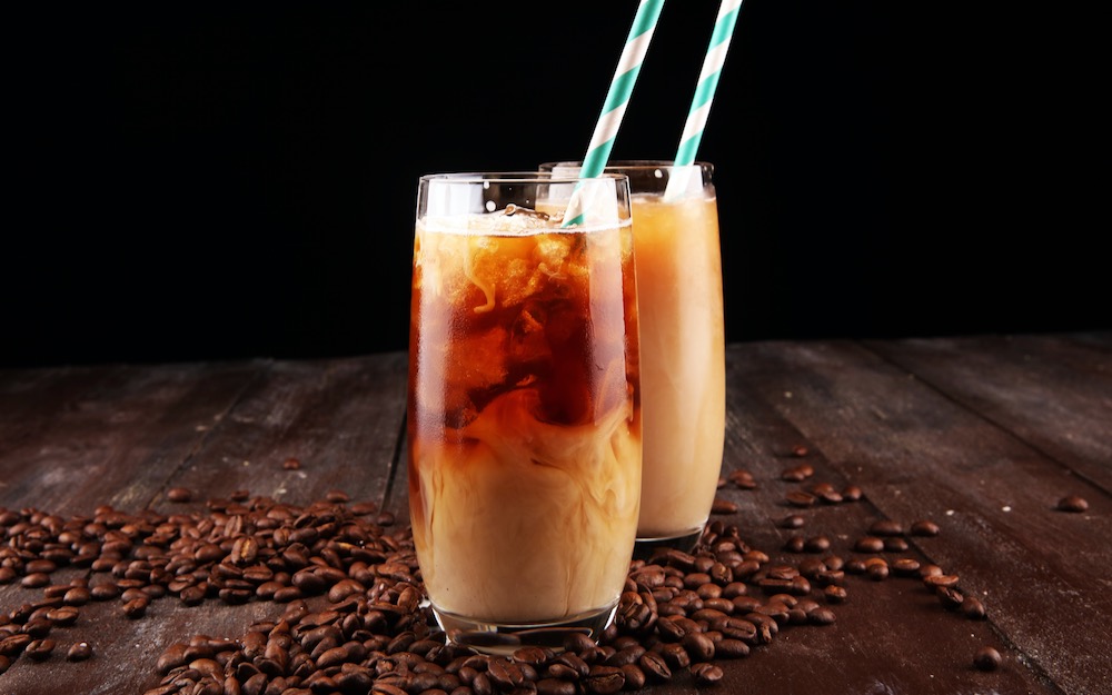 Zwei Coffee cocktails im Glas mit Strohhalmen auf Holztisch mit Espressobohnen