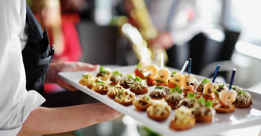 Servicepersonal mit Flying Fingerfood Buffet auf Firmenveranstaltung hält Tablett