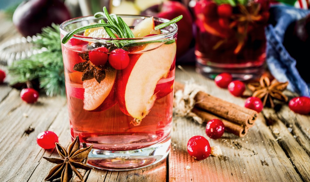 Heisser Cocktail mit Apfel und Zimtstangen auf Holzhintergrund