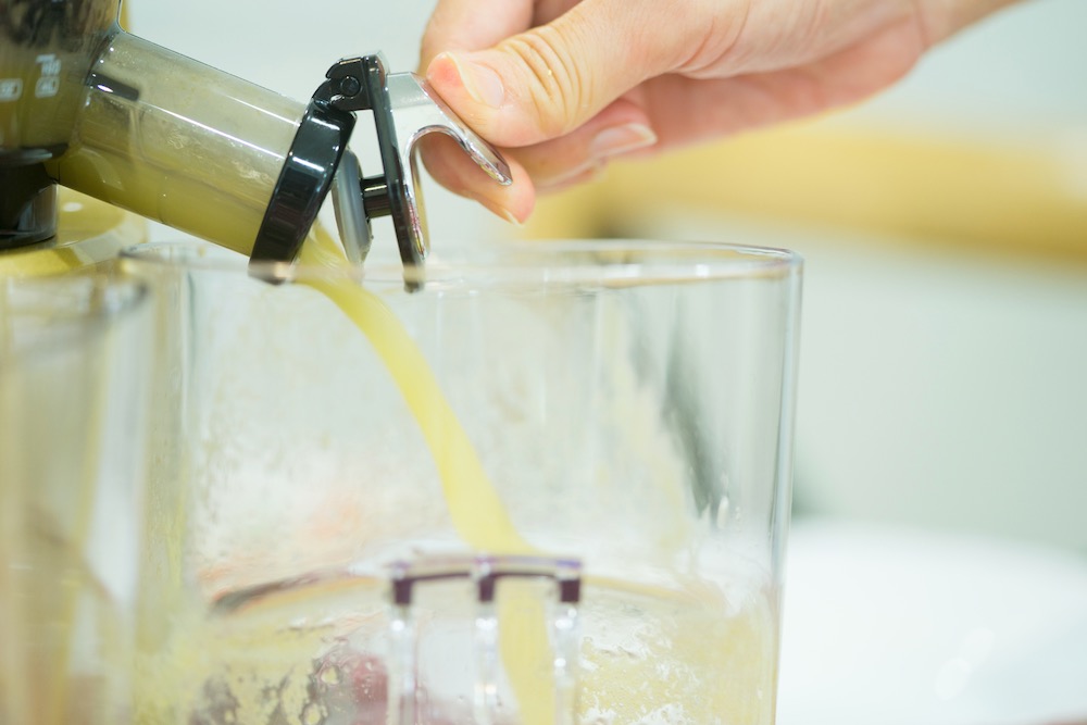 Saft läuft aus Entsafter in ein Glas